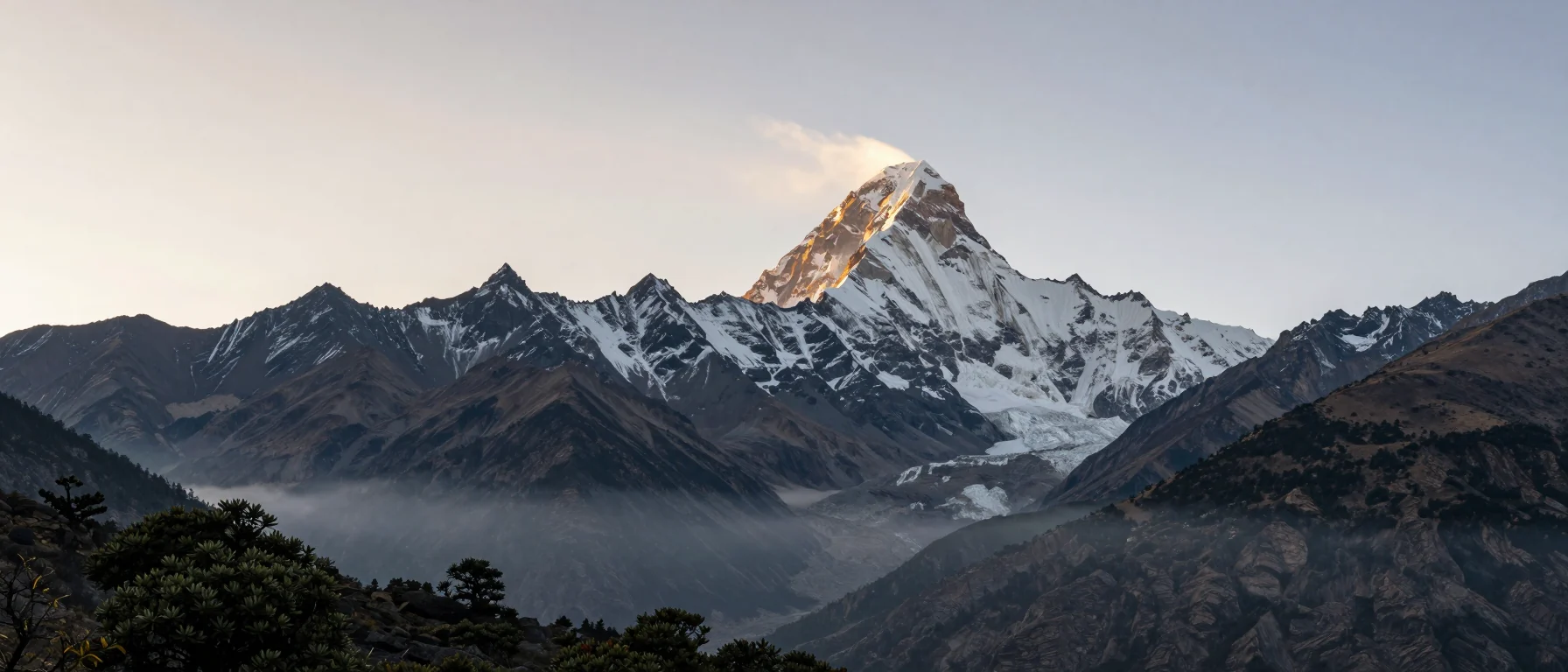 Everest at sunrise, a snow-covered summit catching first light above misty Himalayan valleys, Nepal