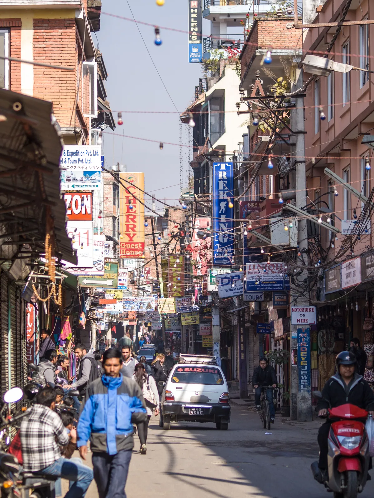 A busy shopping street in Kathmandu with hanging lights and shop signs