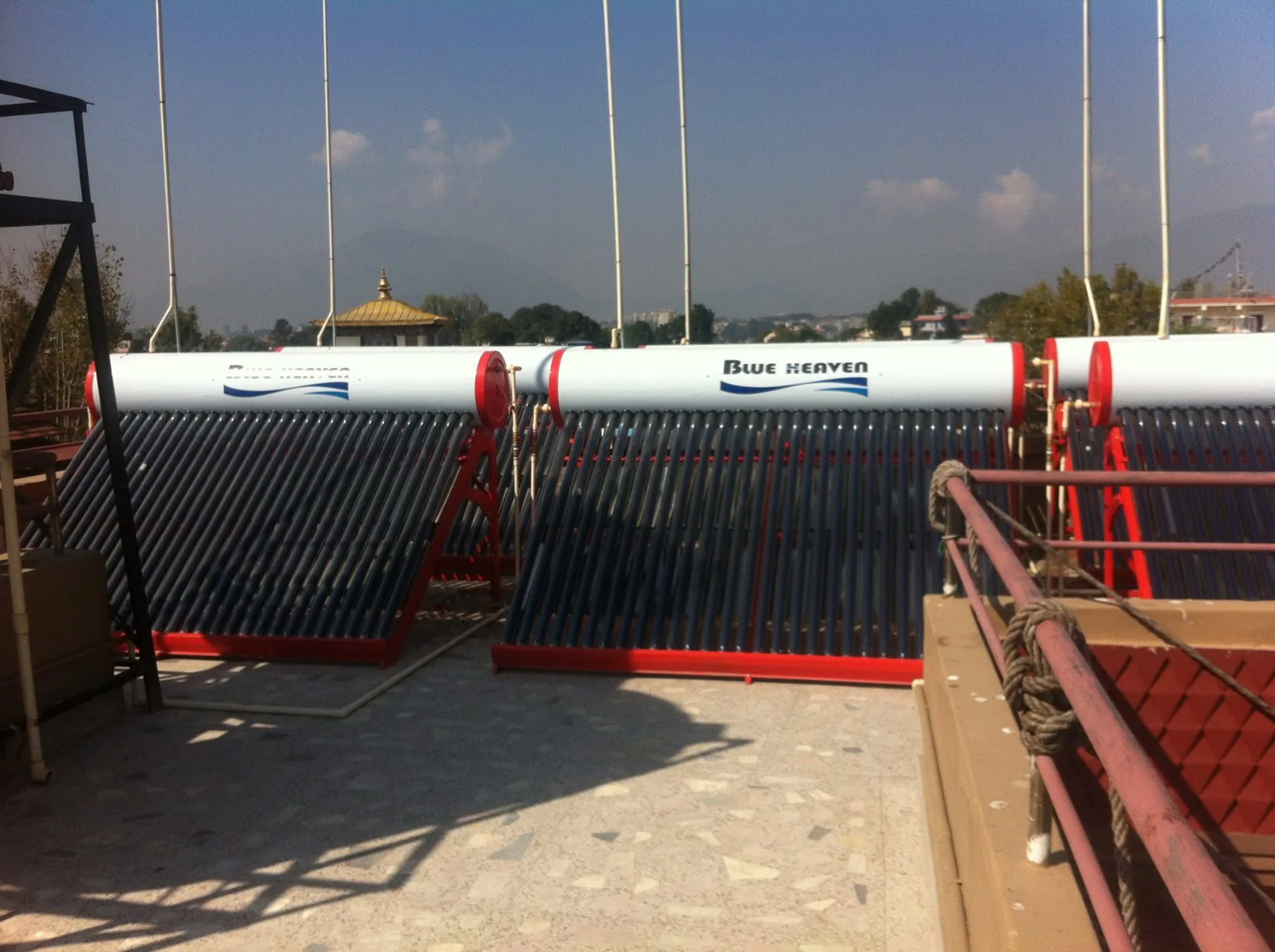 Blue Heaven solar water heaters on a Kathmandu rooftop with a golden pagoda behind